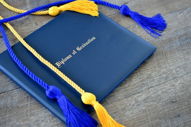 Flat lay of a diploma of graduation with honor cords on a simple wooden background achievement t20 o R19a W